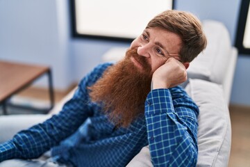 Wall Mural - Young redhead man smiling confident sitting on sofa at home