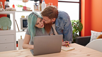 Wall Mural - Man and woman couple using laptop writing notebook at dinning room