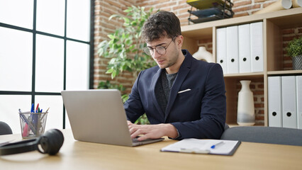 Wall Mural - Young hispanic man business worker using laptop with serious face at office