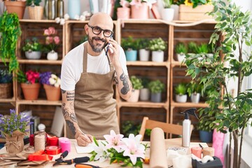 Poster - Young bald man florist talking on smartphone writing on notebook at florist