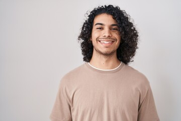 Wall Mural - Hispanic man with curly hair standing over white background with a happy and cool smile on face. lucky person.