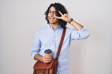 Sticker - Hispanic man with curly hair drinking a cup of take away coffee doing peace symbol with fingers over face, smiling cheerful showing victory