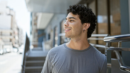 Wall Mural - Young latin man smiling confident looking to the side at street