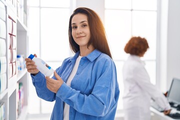 Wall Mural - Two women pharmacist and customer holding bottle at pharmacy