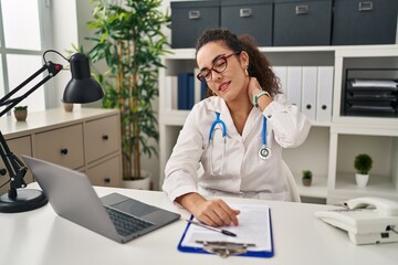 Canvas Print - Young hispanic woman wearing doctor uniform and stethoscope suffering of neck ache injury, touching neck with hand, muscular pain