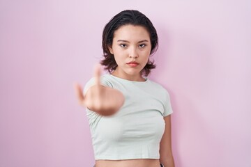 Sticker - Hispanic young woman standing over pink background showing middle finger, impolite and rude fuck off expression