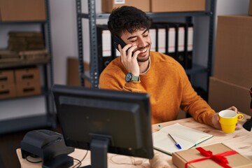 Canvas Print - Young hispanic man ecommerce business worker talking on smartphone drinking coffee at office