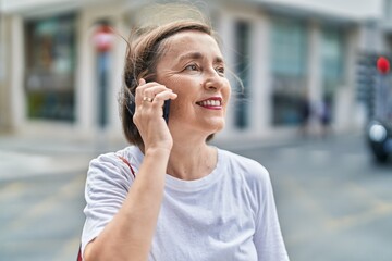 Wall Mural - Middle age woman smiling confident talking on the smartphone at street