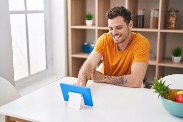 Canvas Print - Young hispanic man watching video on touchpad at home