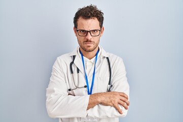 Young hispanic man wearing doctor uniform and stethoscope skeptic and nervous, disapproving expression on face with crossed arms. negative person.