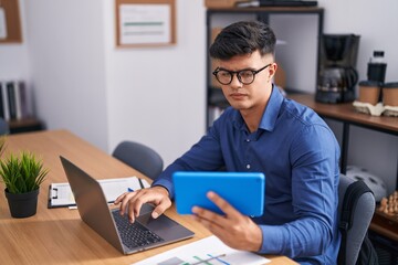 Canvas Print - Young hispanic man business worker using touchpad and laptop at office