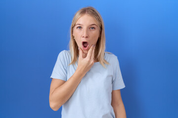 Sticker - Young caucasian woman wearing casual blue t shirt looking fascinated with disbelief, surprise and amazed expression with hands on chin