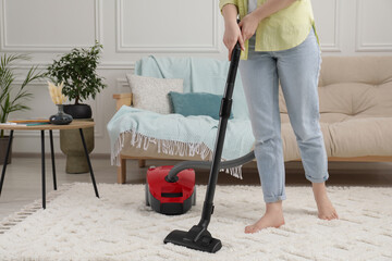 Wall Mural - Woman cleaning carpet with vacuum cleaner at home, closeup. Space for text