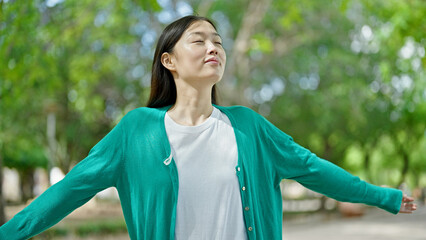 Wall Mural - Young chinese woman smiling confident breathing at park