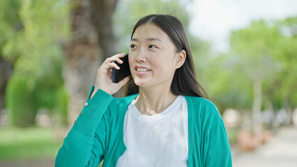 Wall Mural - Young chinese woman talking on smartphone smiling at park