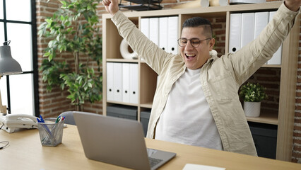 Sticker - Young hispanic man business worker using laptop celebrating at office