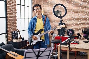 Poster - Young hispanic man musician playing electrical guitar recording video at music studio