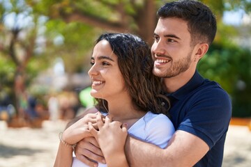 Wall Mural - Young hispanic couple smiling confident hugging each other at park