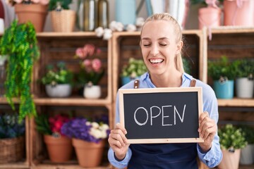 Poster - Young caucasian woman working at florist holding open sign smiling and laughing hard out loud because funny crazy joke.