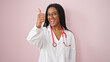 © Krakenimages.com - African american woman doctor doing thumb up over isolated pink background