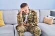 © Krakenimages.com - Young hispanic man army soldier sitting on sofa stressed at home