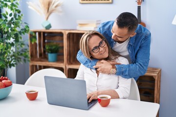 Canvas Print - Man and woman mother and son drinking coffee using laptop at home