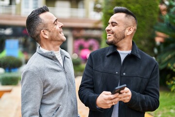 Canvas Print - Two men couple smiling confident using smartphone at park