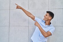 Young Hispanic Man Smiling Confident Pointing With Fingers To The Sky At Street