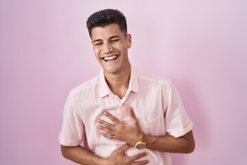 Canvas Print - Young hispanic man standing over pink background smiling and laughing hard out loud because funny crazy joke with hands on body.