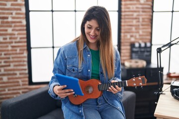 Sticker - Young hispanic woman musician using touchpad holding ukulele at music studio