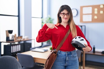 Sticker - Young brunette woman working at the office holding bike helmet pointing finger to one self smiling happy and proud