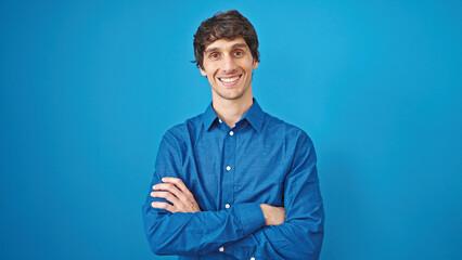 Poster - Young hispanic man smiling confident standing with arms crossed gesture over isolated blue background