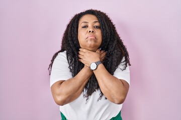 Wall Mural - Plus size hispanic woman standing over pink background shouting suffocate because painful strangle. health problem. asphyxiate and suicide concept.