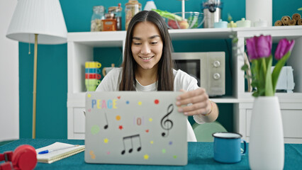 Poster - Young beautiful hispanic woman using laptop sitting on table at dinning room