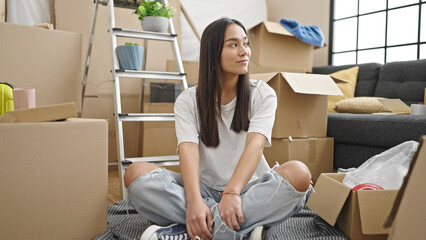 Wall Mural - Young beautiful hispanic woman smiling confident sitting on floor at new home