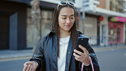 Poster - Young beautiful hispanic woman using smartphone holding shopping bags at street