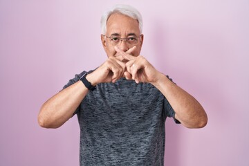 Wall Mural - Middle age man with grey hair standing over pink background rejection expression crossing fingers doing negative sign