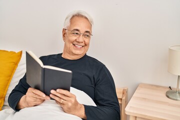 Wall Mural - Senior man reading book sitting on bed at bedroom