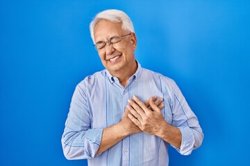 Wall Mural - Hispanic senior man wearing glasses smiling with hands on chest with closed eyes and grateful gesture on face. health concept.