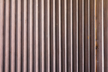 Closed rolling door steel stripe texture with faded paint color. Abandoned rusty rolling door steel. Rusty metal rolling shutter wall Material texture background.