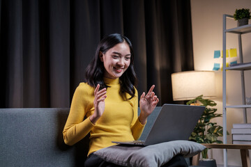Aufkleber - Asian young woman chatting online on laptop computer while sitting on sofa late at night