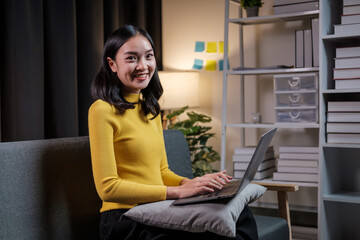 Aufkleber - Happy asian woman sitting on sofa in living room, using laptop