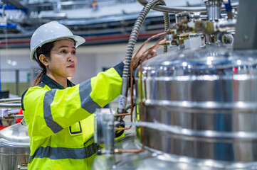 Asian engineer working at Operating hall,Thailand people wear helmet  work,He worked with diligence and patience,she checked the valve regulator at the hydrogen tank.