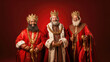 Christmas tradition. The Three Wise Men smiling with robes and crowns over red background with copy space