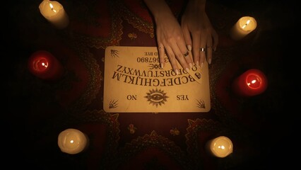 Spirit board laying on the table, female hands moving over it, showing different words.