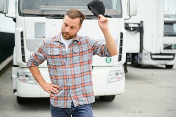 Canvas Print - Tired from the road, the truck driver is standing near to his white truck.