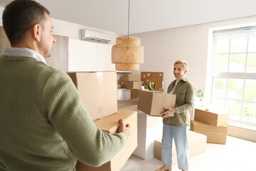 Poster - Mature couple with cardboard boxes in kitchen on moving day