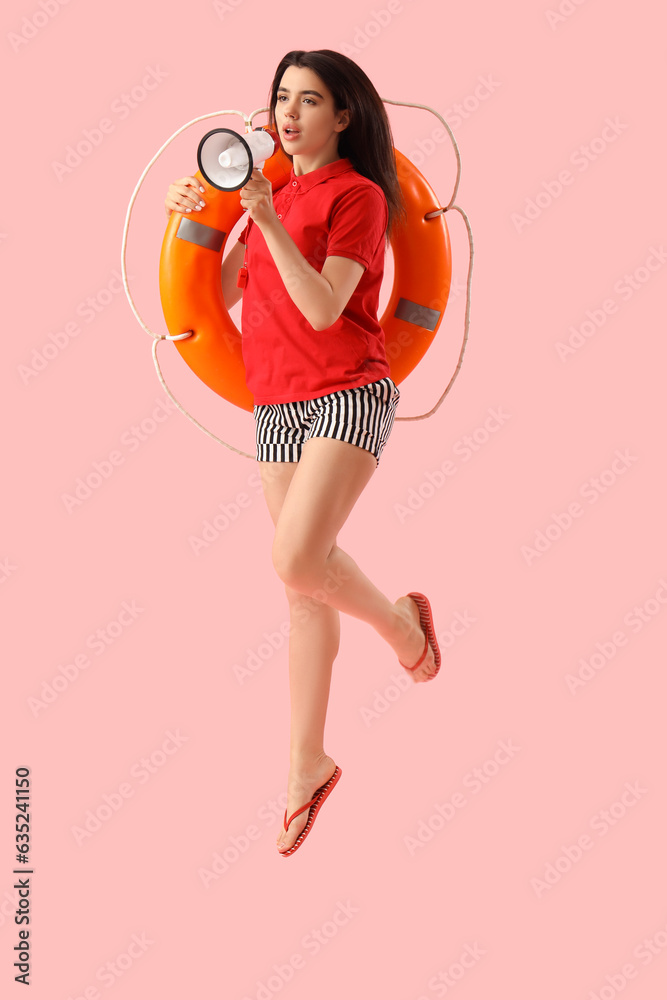Female lifeguard with megaphone and ring buoy jumping on pink background