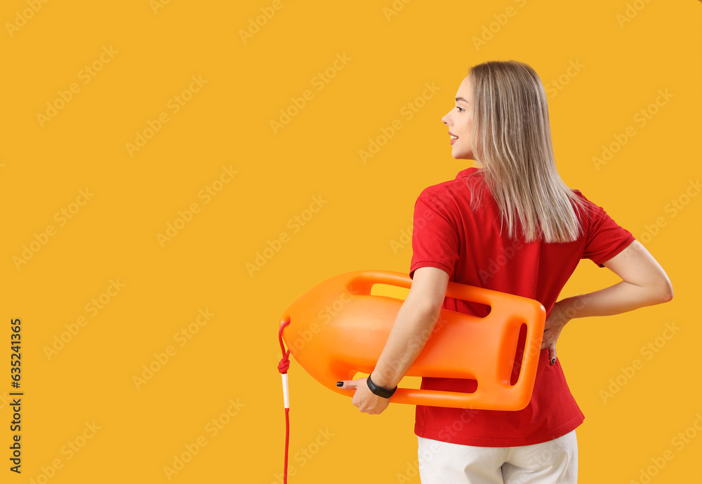 Female lifeguard with rescue buoy on yellow background, back view