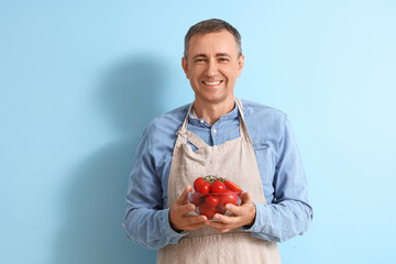 Canvas Print - Mature man with fresh tomatoes on blue background